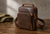 Coffee brown leather messenger bag on a walnut table