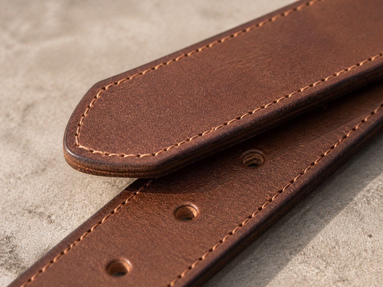 Rounded leather belt tip, clean holes and stitched finished edges
